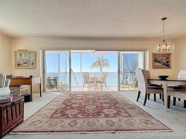 dining area with a chandelier, carpet, a healthy amount of sunlight, and a textured ceiling