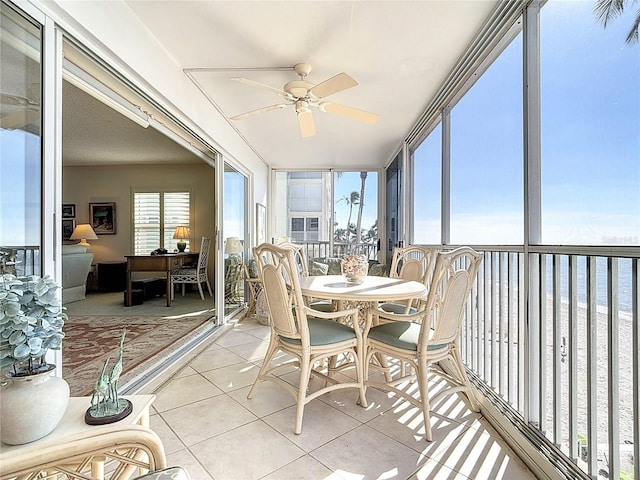 sunroom / solarium with ceiling fan and a water view