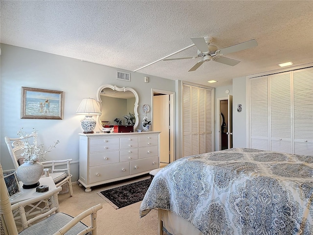 bedroom featuring ceiling fan, light carpet, and a textured ceiling