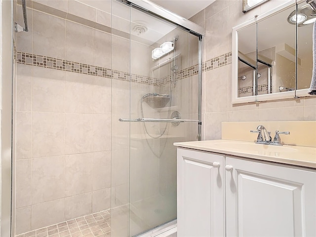 bathroom with walk in shower, vanity, tile walls, and backsplash