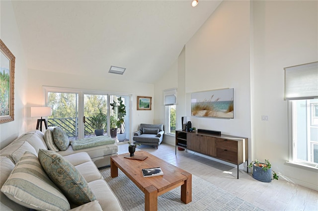 living room featuring a healthy amount of sunlight, light wood-type flooring, and high vaulted ceiling