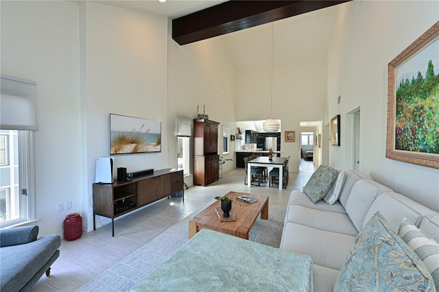 living room featuring beamed ceiling, light hardwood / wood-style flooring, high vaulted ceiling, and plenty of natural light