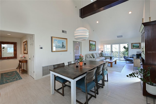 dining area with beam ceiling, light hardwood / wood-style flooring, and high vaulted ceiling