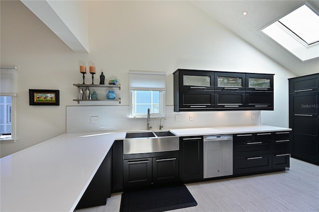 kitchen with a skylight, sink, light hardwood / wood-style flooring, high vaulted ceiling, and backsplash