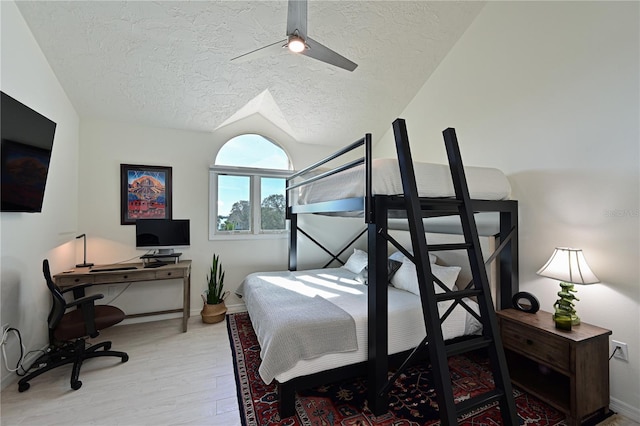 bedroom with a textured ceiling, ceiling fan, lofted ceiling, and light wood-type flooring