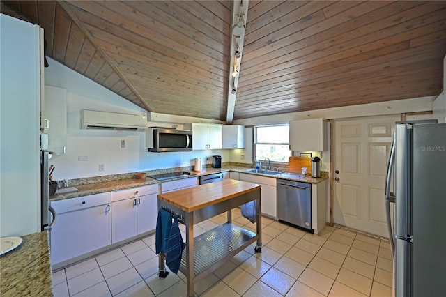 kitchen featuring stainless steel appliances, vaulted ceiling, sink, an AC wall unit, and white cabinetry