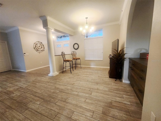 dining area with light wood-type flooring, decorative columns, an inviting chandelier, and ornamental molding