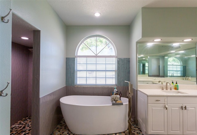 bathroom with vanity, shower with separate bathtub, a textured ceiling, and a wealth of natural light