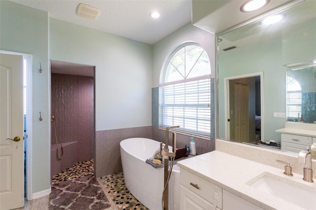 bathroom featuring vanity, a textured ceiling, and plus walk in shower