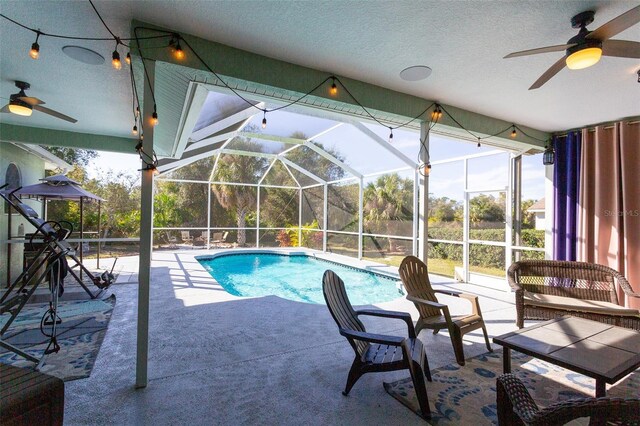 view of swimming pool featuring a lanai, ceiling fan, and a patio area