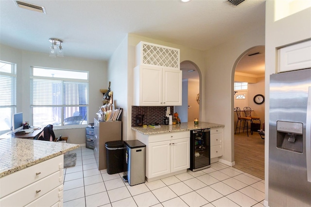 kitchen with white cabinetry, light stone countertops, stainless steel fridge, and wine cooler