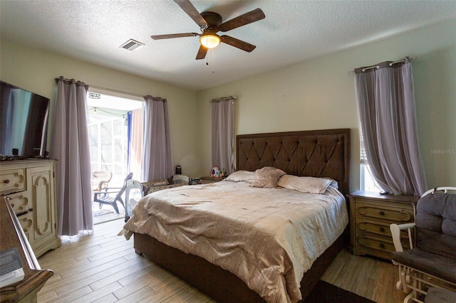 bedroom featuring ceiling fan, access to exterior, light wood-type flooring, and a textured ceiling