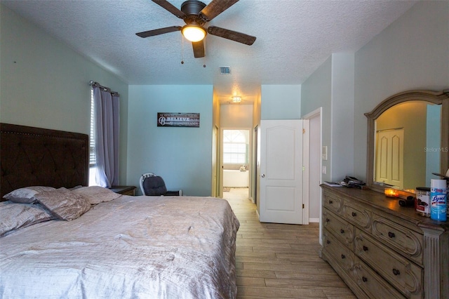 bedroom with a textured ceiling, ceiling fan, and light hardwood / wood-style flooring