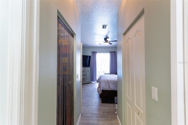 hallway featuring wood-type flooring and a textured ceiling