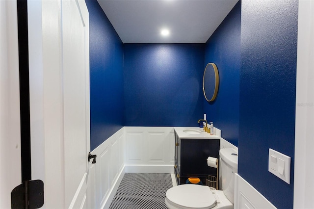 bathroom with toilet, vanity, and tile patterned flooring