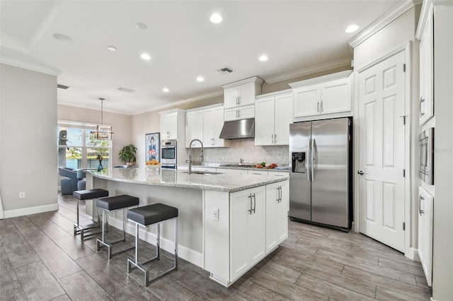 kitchen with stainless steel appliances, sink, white cabinets, a breakfast bar area, and an island with sink