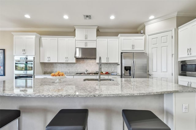 kitchen with white cabinets, a large island, exhaust hood, and appliances with stainless steel finishes