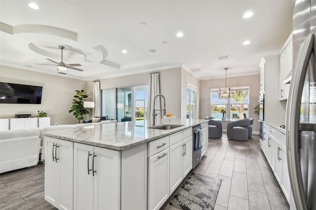 kitchen with light stone countertops, white cabinetry, sink, an island with sink, and pendant lighting