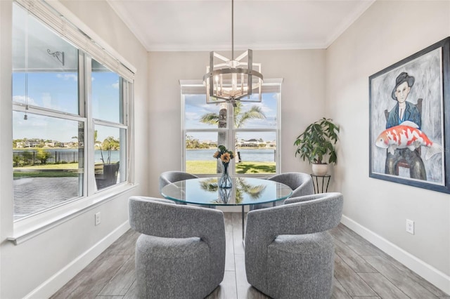 dining area with wood-type flooring, a water view, ornamental molding, and a notable chandelier