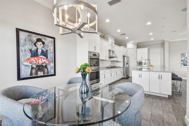 living room with a chandelier, light hardwood / wood-style flooring, ornamental molding, and sink