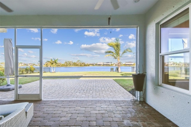 unfurnished sunroom with ceiling fan, a healthy amount of sunlight, and a water view