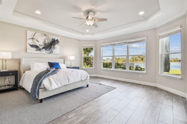 bedroom with ceiling fan, light hardwood / wood-style flooring, and a tray ceiling