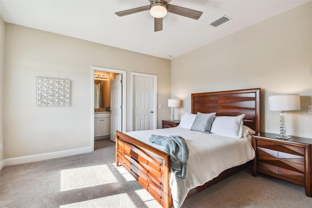 bedroom with ceiling fan, light colored carpet, and connected bathroom