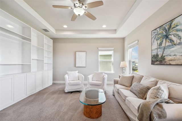 carpeted living room featuring a tray ceiling and ceiling fan