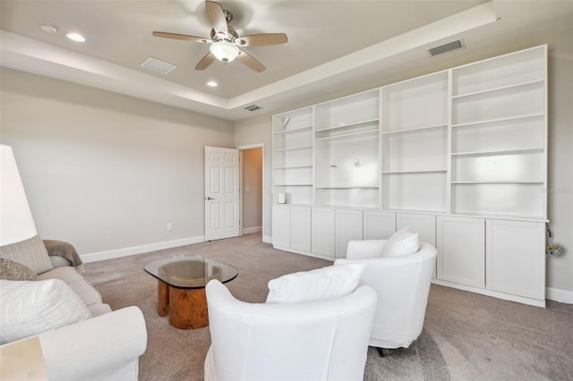 living room featuring ceiling fan, a raised ceiling, and light colored carpet