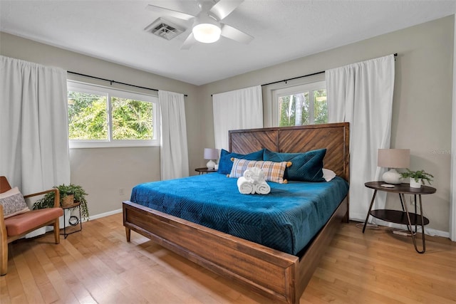 bedroom featuring multiple windows, light wood-type flooring, and ceiling fan