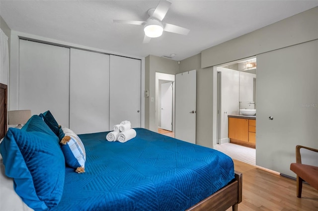 bedroom with a closet, light hardwood / wood-style flooring, ceiling fan, and ensuite bathroom