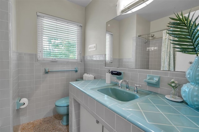 bathroom with curtained shower, vanity, tile walls, and toilet