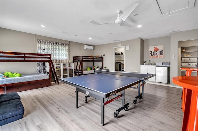 playroom featuring sink, ceiling fan, independent washer and dryer, light hardwood / wood-style floors, and a wall unit AC