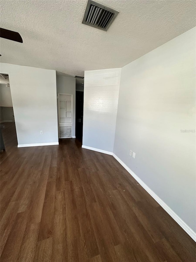 spare room with a textured ceiling, dark hardwood / wood-style floors, and ceiling fan