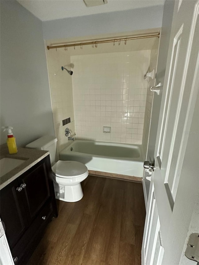 full bathroom featuring hardwood / wood-style floors, vanity, toilet, and tiled shower / bath