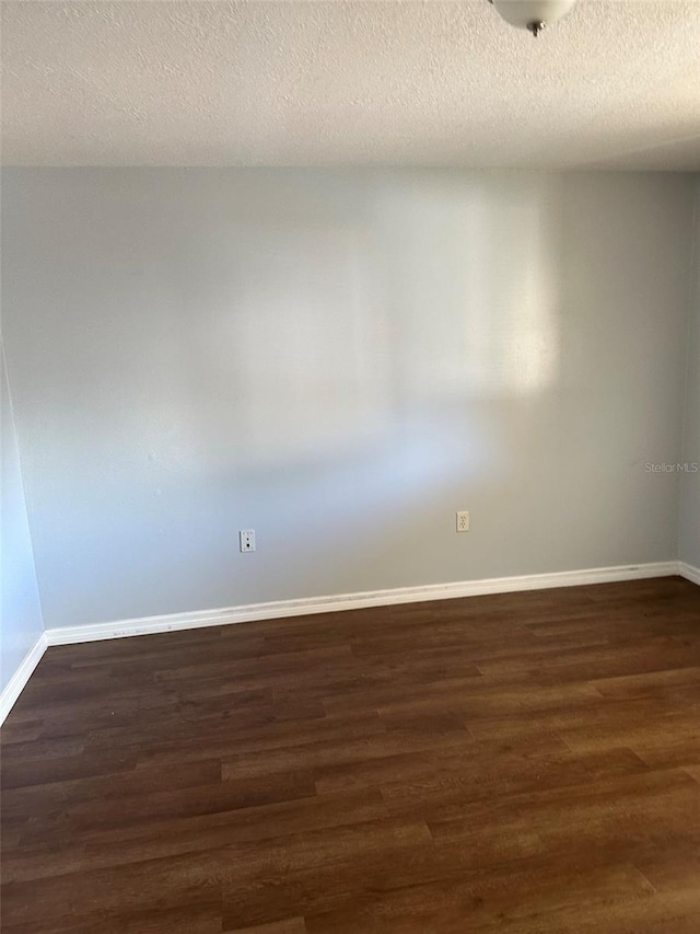 spare room with dark hardwood / wood-style flooring and a textured ceiling