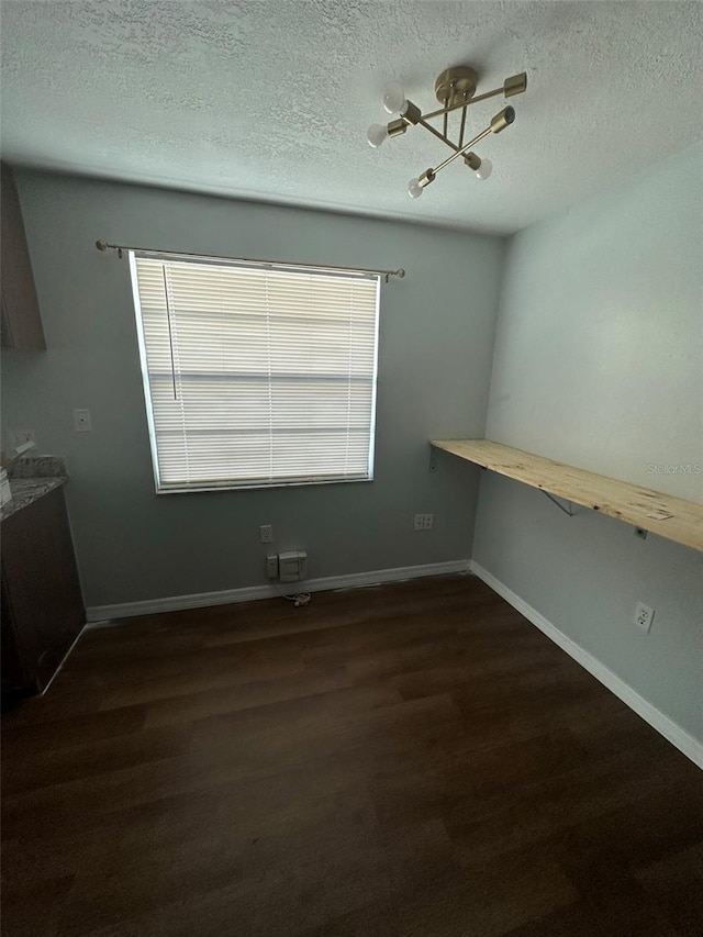 interior space featuring a textured ceiling, built in desk, dark hardwood / wood-style floors, and an inviting chandelier