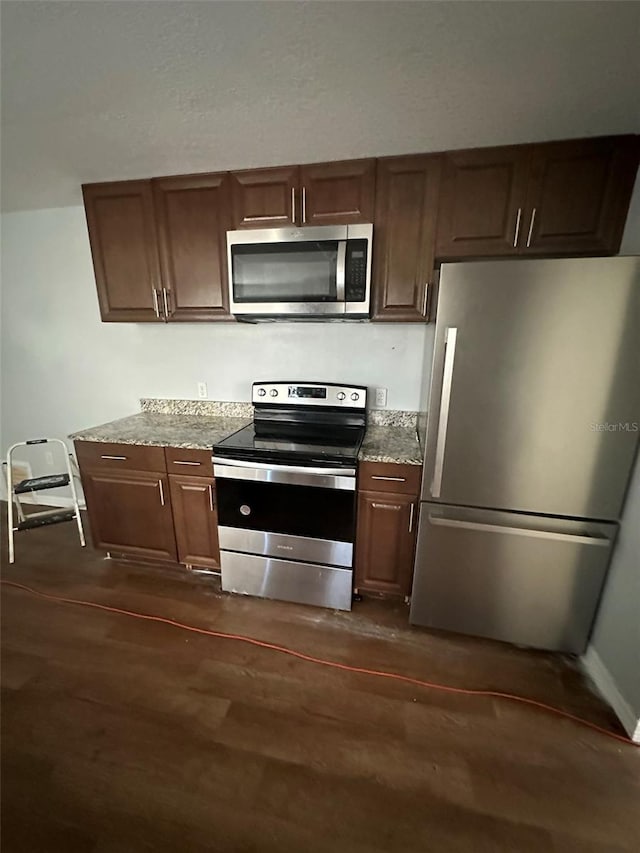 kitchen featuring light stone counters, dark hardwood / wood-style flooring, and stainless steel appliances