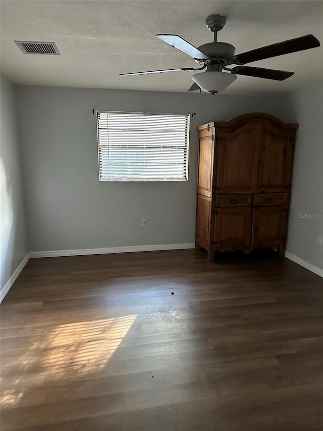 unfurnished bedroom with ceiling fan and dark wood-type flooring