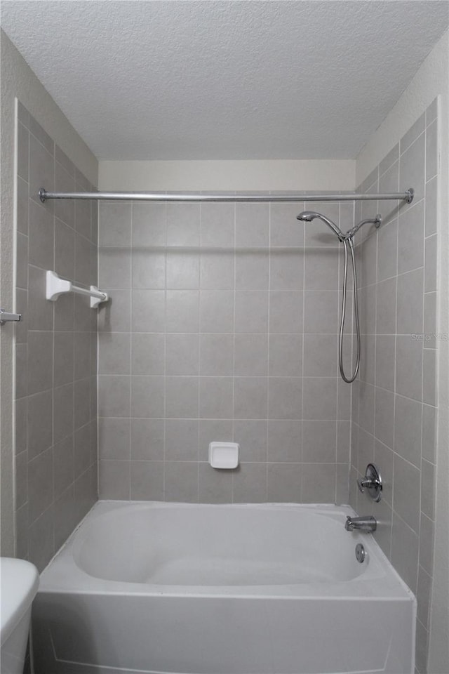 bathroom featuring tiled shower / bath combo, a textured ceiling, and toilet