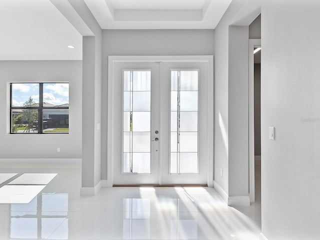 doorway featuring french doors, a tray ceiling, and light tile patterned flooring