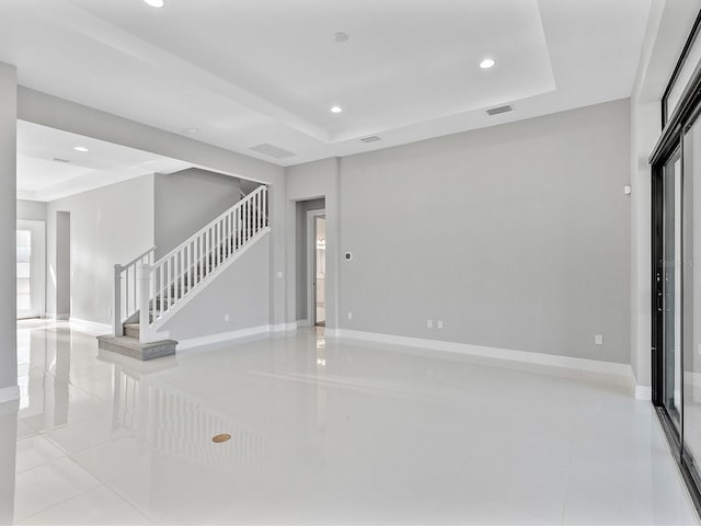 unfurnished living room featuring a raised ceiling and light tile patterned floors