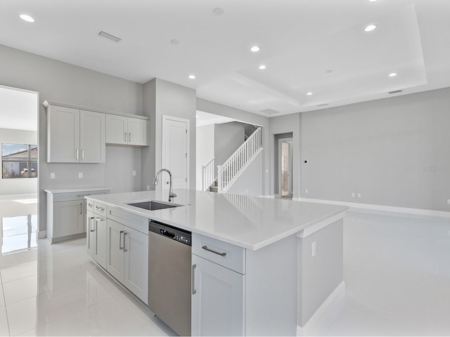 kitchen featuring light stone counters, sink, a center island with sink, dishwasher, and gray cabinets