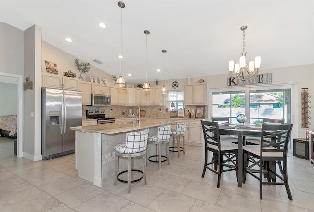 kitchen with light stone countertops, stainless steel appliances, an island with sink, decorative light fixtures, and a breakfast bar area