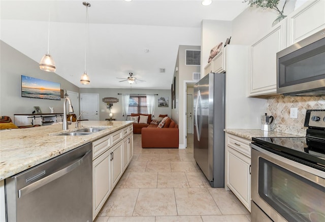 kitchen featuring light stone countertops, appliances with stainless steel finishes, ceiling fan, sink, and decorative light fixtures