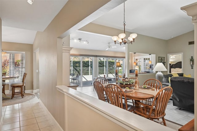 tiled dining room with ceiling fan with notable chandelier and lofted ceiling