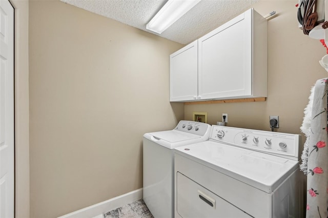 washroom with cabinets, a textured ceiling, and washing machine and clothes dryer