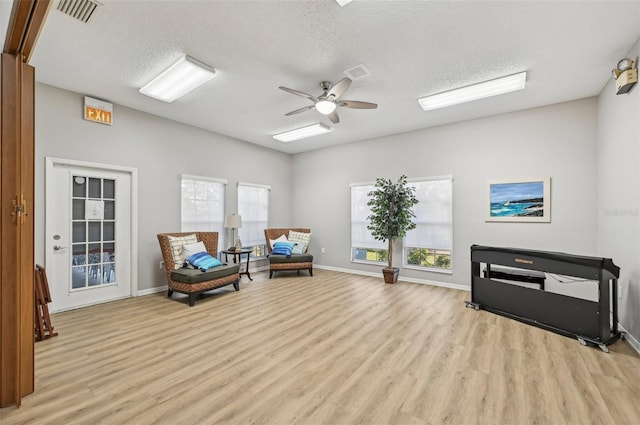 sitting room with a textured ceiling, light wood-type flooring, and ceiling fan