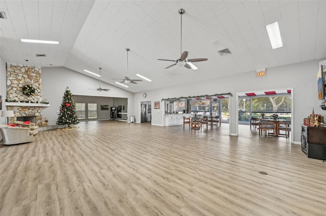 workout area featuring ceiling fan, light wood-type flooring, a fireplace, and high vaulted ceiling