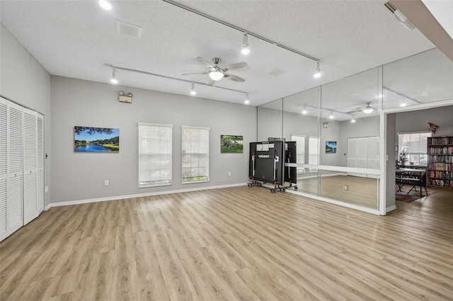 workout area featuring ceiling fan, a textured ceiling, track lighting, and light hardwood / wood-style flooring